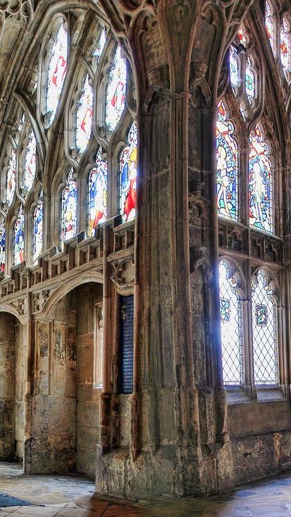 A panoramic view of the Gloucester Cathedral cloisters displaying decorated ceiling and stained glass artwork