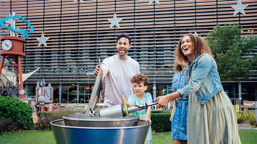Family playing with water at a play station outdoors