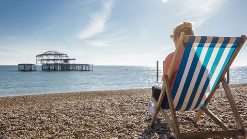 Rear view of woman sitting in striped deckchair on the beach