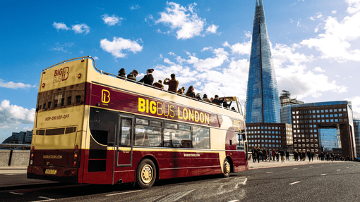 A group of tourists taking pictured from the upper deck of a Big Bug open top London bus tour with the Shard in the backdrop