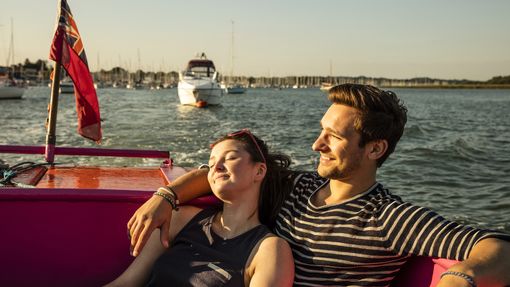 A couple seated on a bench on deck in evening sunshine