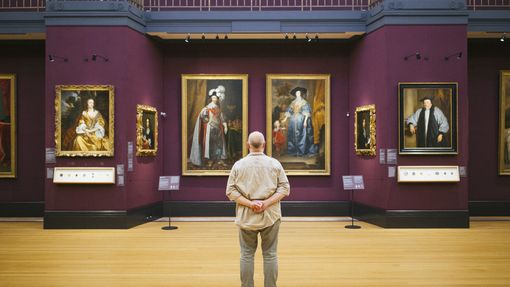 Rear view of man standing looking at portraits in a gallery