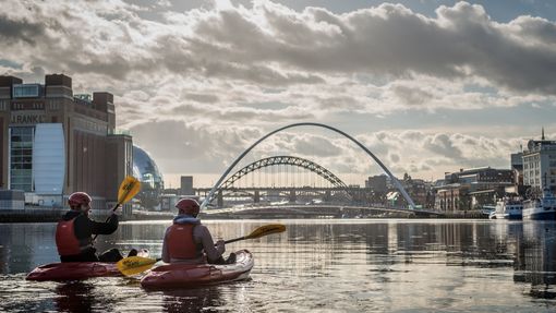 Couple kayaking on a river under blue skies