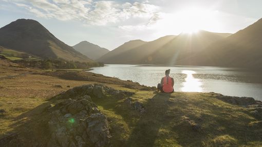Woman, meditating in green valleys, near lake. High sun
