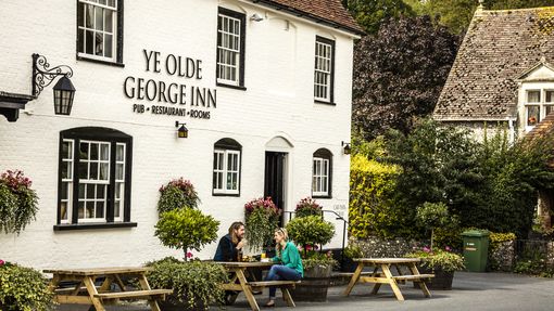 A couple sitting outside the pub on a bench having a drink