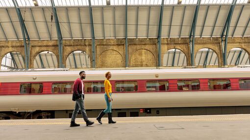 Man and woman walk along a train station platform