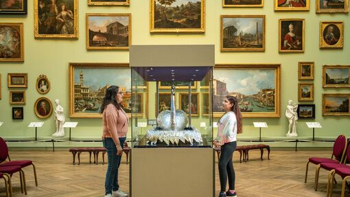 A woman and daughter stand looking at an exhibit in a museum