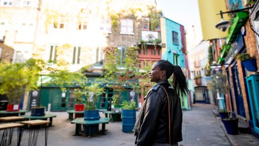 Female tourist exploring a London shopping courtyard with shops and outdoor seating