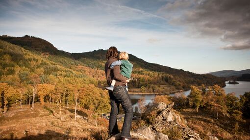 Woman and child standing on a hilltop overlooking a lake