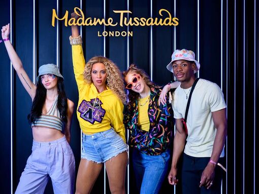 Beyonce at Madame Tussauds along with three young people posing for a photograph
