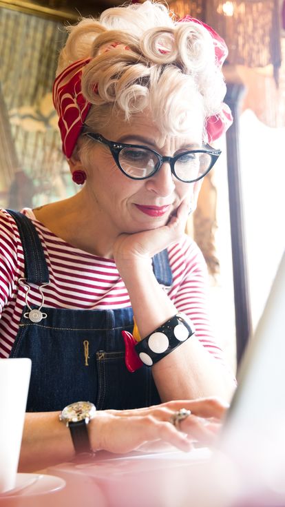 Close_up_of_a_blond_woman_wearing_a_stripy_top_and_red_head_scarf_having_a_coffee_and_looking_down_at_a_lap_top_screen