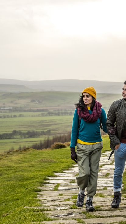 Young couple hiking and walking along a paved footpath.