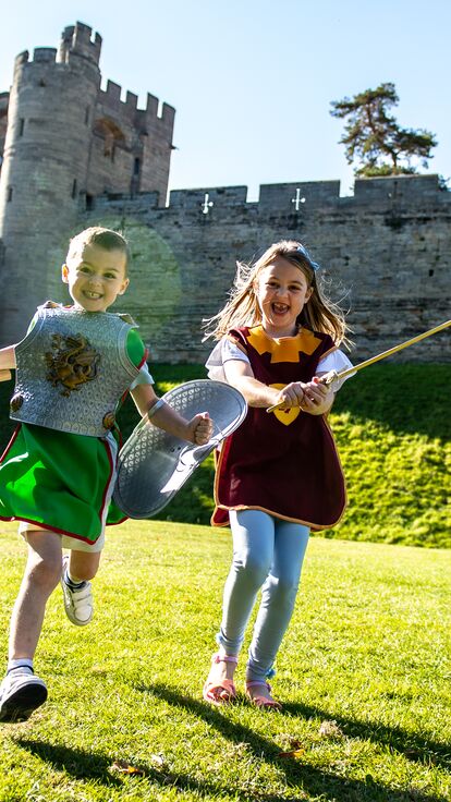 Two girls run, laugh and play with Warwick Castle in the background