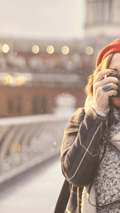 Woman holding a camera on a bridge, taking pictures