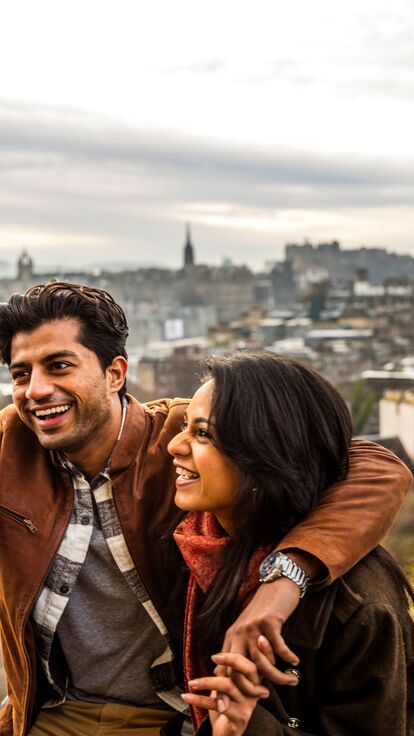 Couple taking a selfie on a mobile phone with Edinburgh in the background