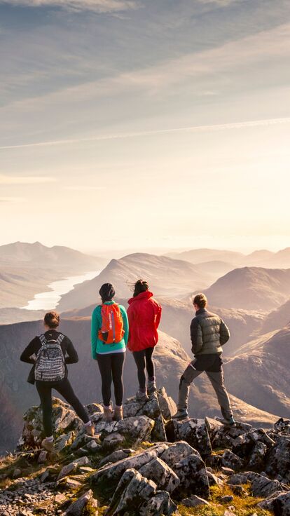 Three hikers looking out at the view in Glen Coe, Scotland