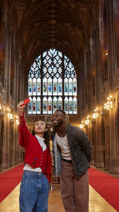 Two people walking through a dramatically lit library in Manchester