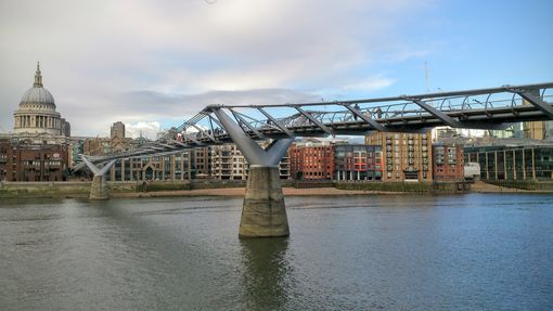 side view of London's Millennium Bridge crossing the river Thames with the dome of St Paul in the distance