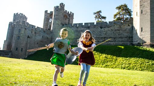 Two girls run, laugh and play with Warwick Castle in the background