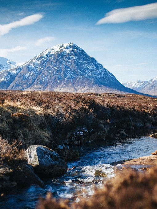 Person sat beside a stream enjoying mountain view