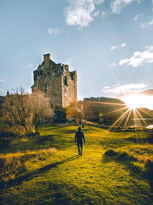 Man walking towards a castle at sunrise