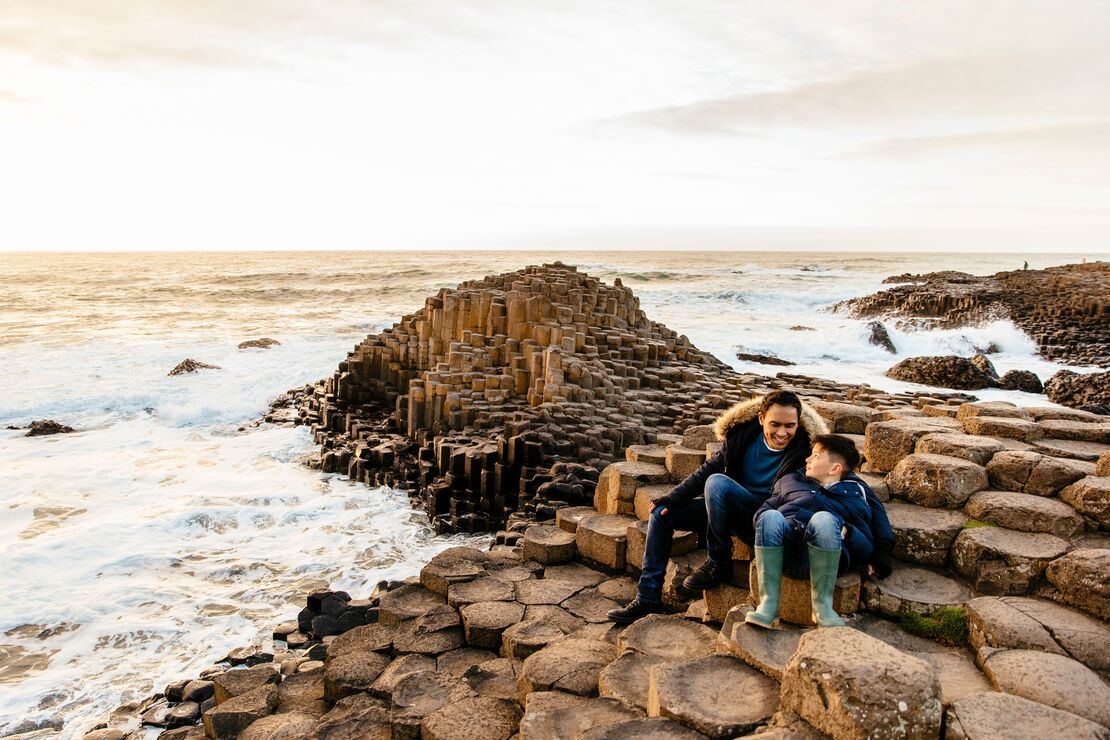 Man and boy sitting on the red basalt columns of Nortern Ireland's Giant Causeway
