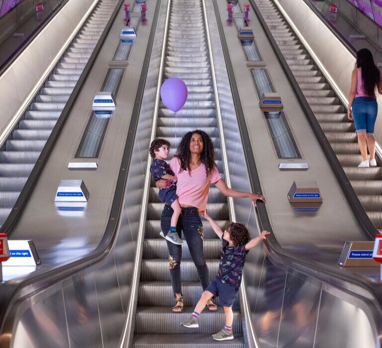 A mum and her two kids on an escalator on the London underground