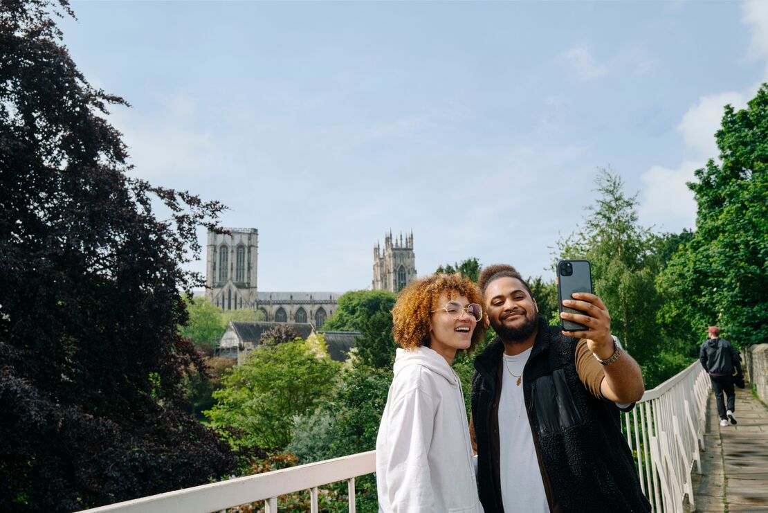 A couple taking a selfie at York City Walls with York Minster in the background