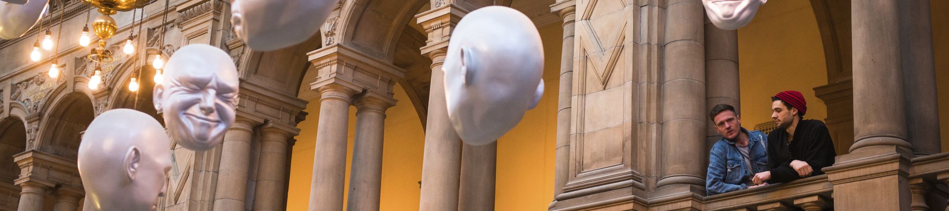 Two men looking at installation of suspended head sculptures - photo by VisitBritain/Tommy Ga-Ken Wan/Sophie Cave