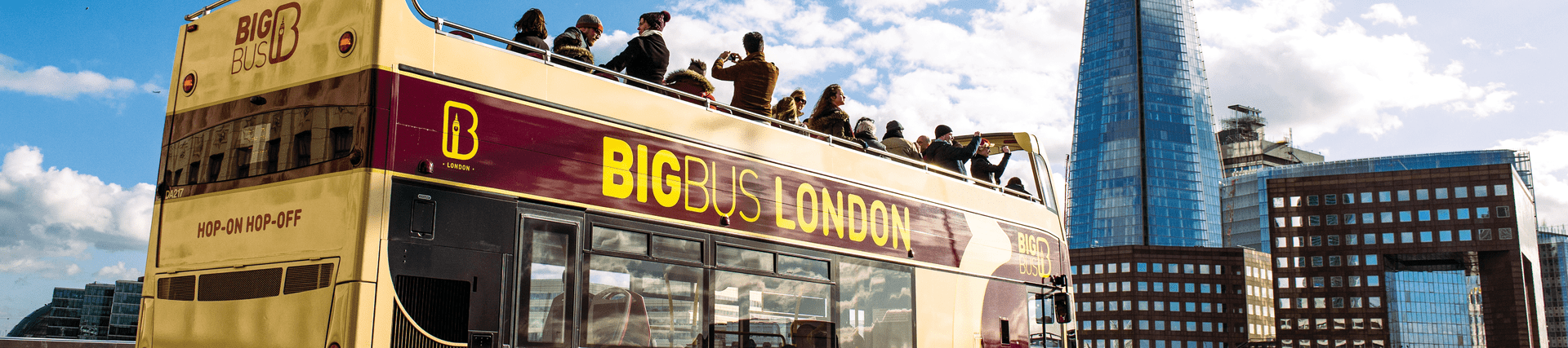 A group of tourists taking pictured from the upper deck of a Big Bug open top London bus tour with the Shard in the backdrop