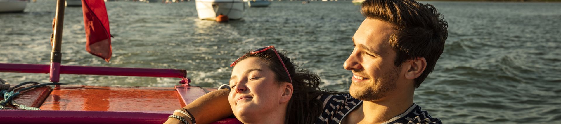 A couple seated on a bench on deck in evening sunshine