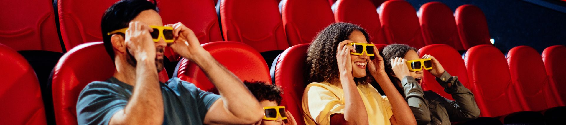 Family with two children sat at a cinema, wearing 3D-glasses