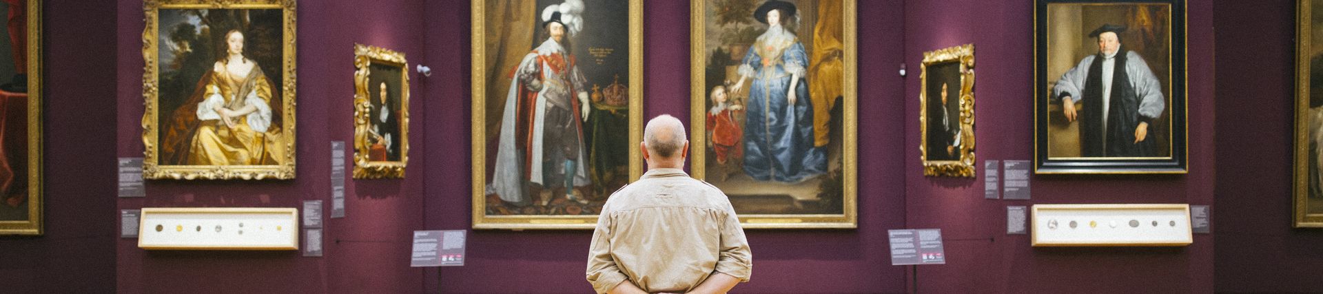 Rear view of man standing looking at portraits in a gallery