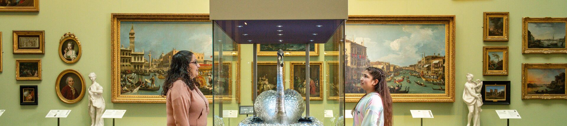 A woman and daughter stand looking at an exhibit in a museum
