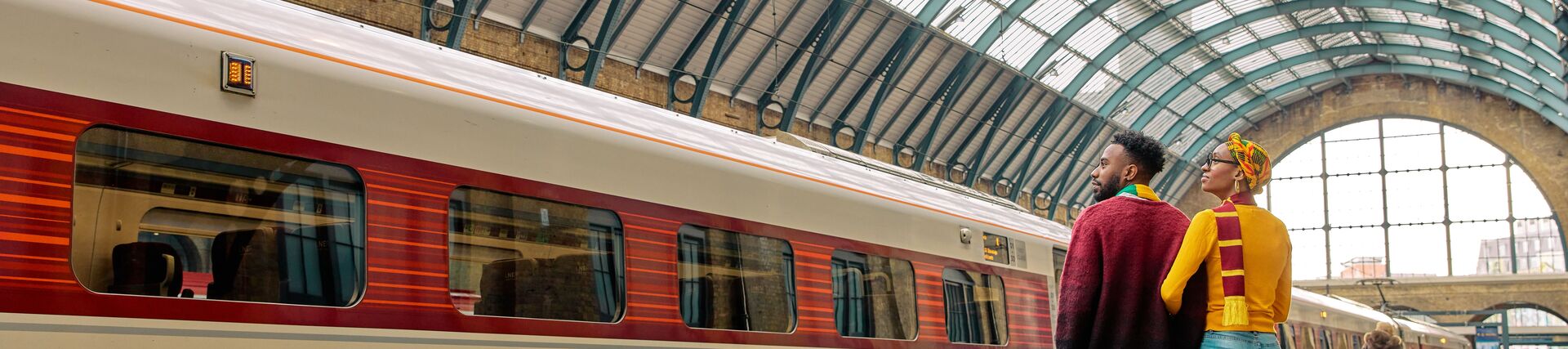A couple standing on a platform, waiting for a train