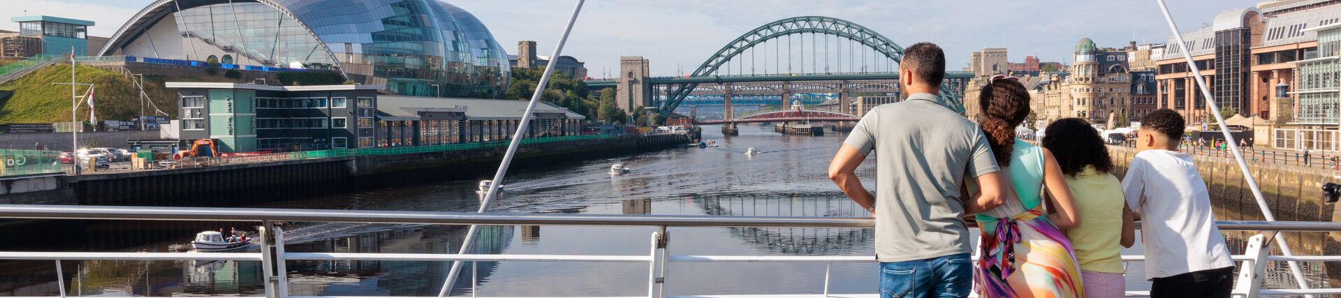 Family standing on a bridge overlooking a city river