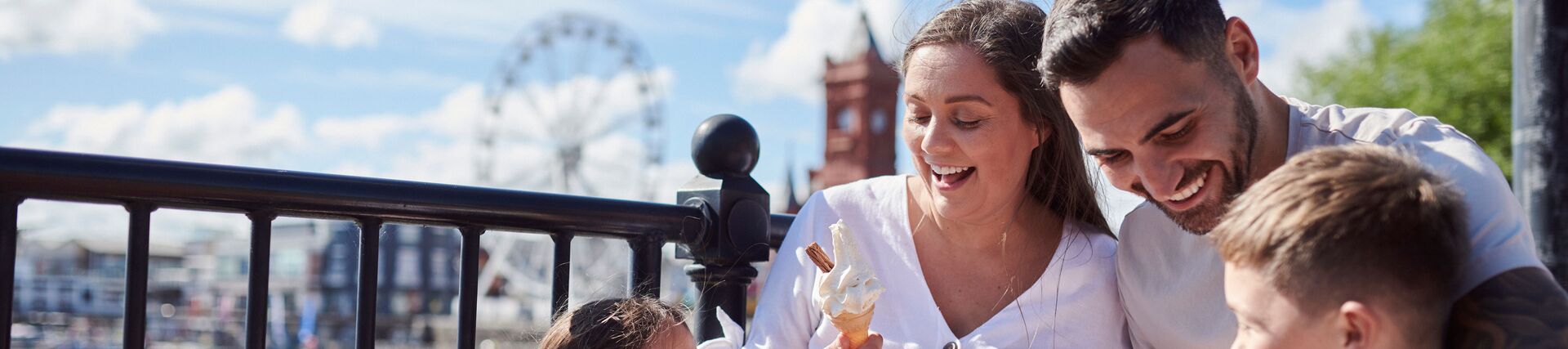 Family eating ice cream in a bay with a Ferris wheel behind