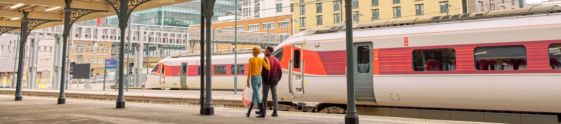Man and woman walk along a train station platform