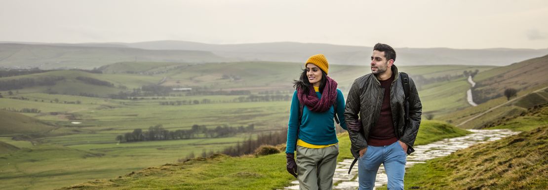 Young couple hiking and walking along a paved footpath.