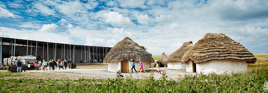 Young tourist explore the Stonehenge museum area with a reconstruction of ancient houses nearby