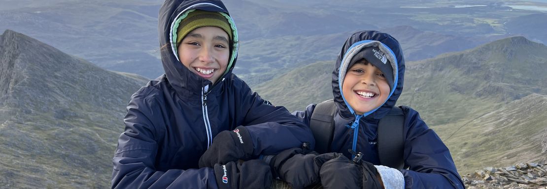 Two children have climbed up to see Mount Snowdon from above and are happy