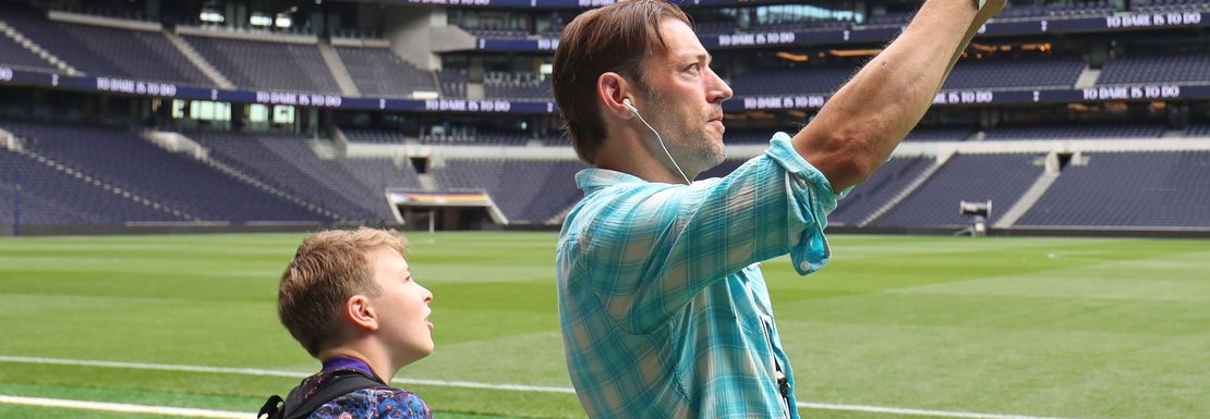 A father and son at pitchside are amazed by the Tottenham stadium.
