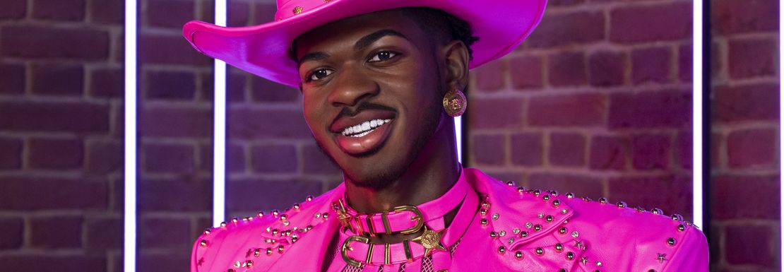 A smiling Lil Nas X in a pink cowboy hat and clothing joins the wax figures at Madame Tussauds in London