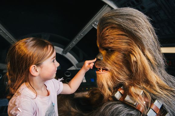 A young girl touches the nose of Chewbacca from Star Wars
