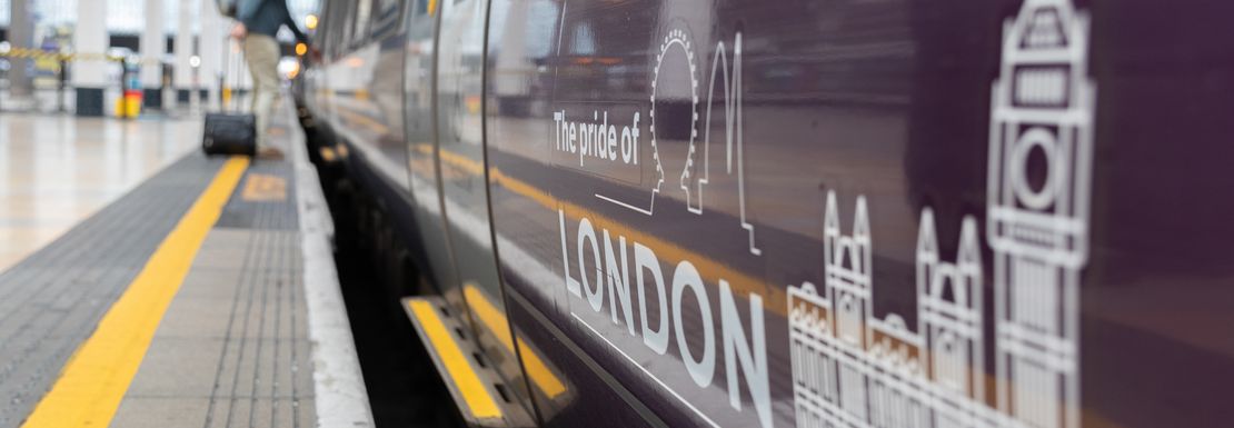 The Pride of London is written on the side of a Heathrow Express train with a man boarding the train