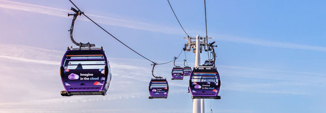 Three cable cars soar through the light blue sky as sunset approaches