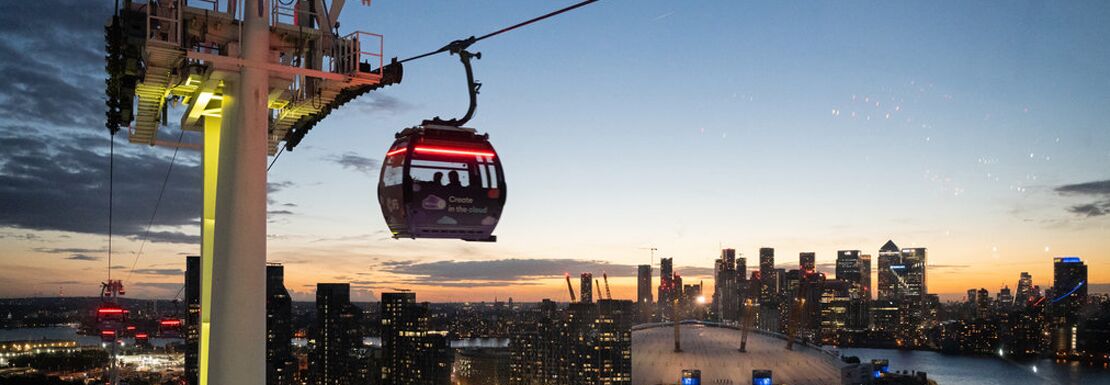 The IFS Cloud Cable Car with Canary Wharft lit up in the evening