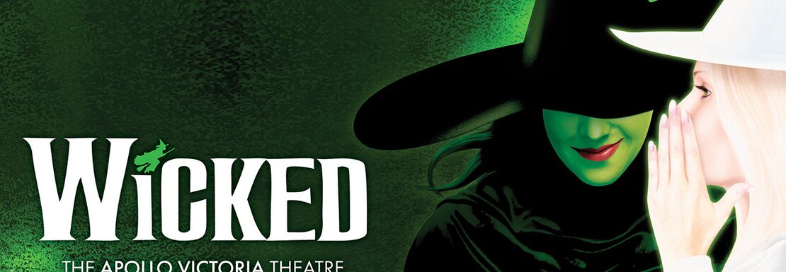 Glinda whispers something into The Wicked Witch of the West's ear in Wicked