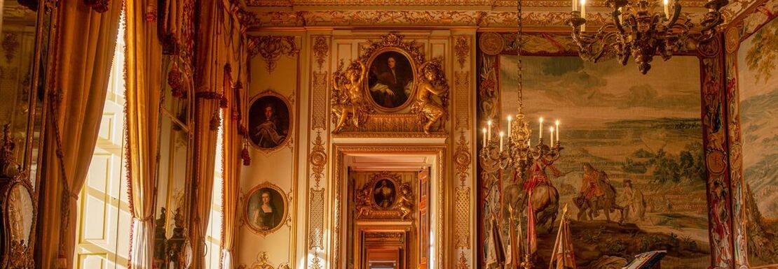 An ornate indoor room inside Blenheim Palace stretches out in front of a long hallway