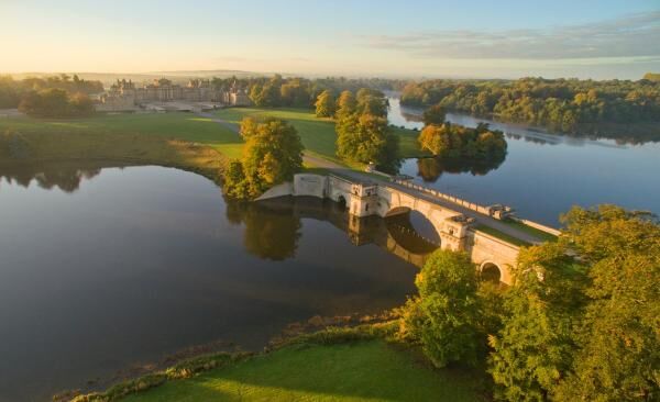 A bridge stretches across two land masses and a beautiful lake surrounded by forest